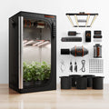 Black indoor grow tent with leafy plants, LED lights, ventilation fan, control panel, pots, cables, and accessories